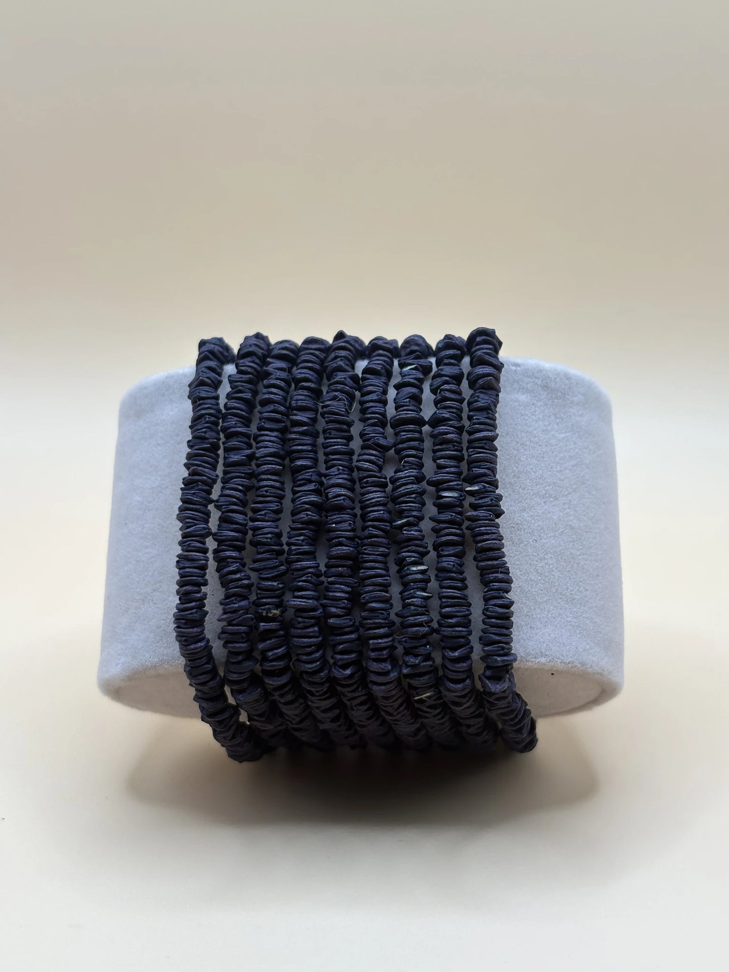 Long collier en graines de morototo teintes en noir, enroulé sur support
